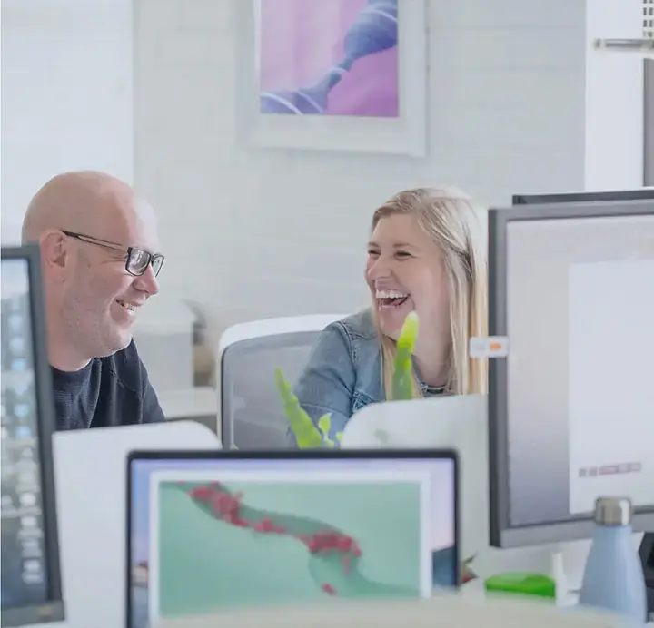 Two people at a desk laughing and having fun at work